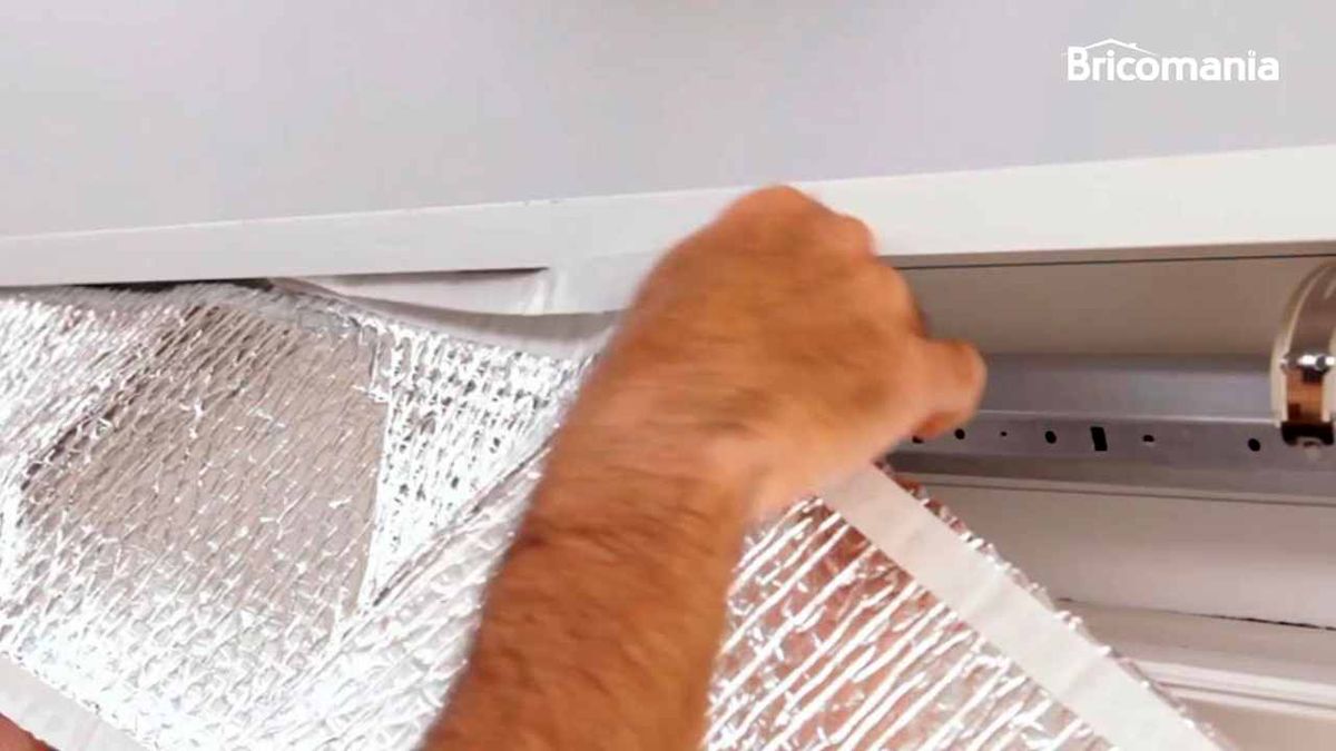 Persona coloca una lámina aislante en la caja de la persiana