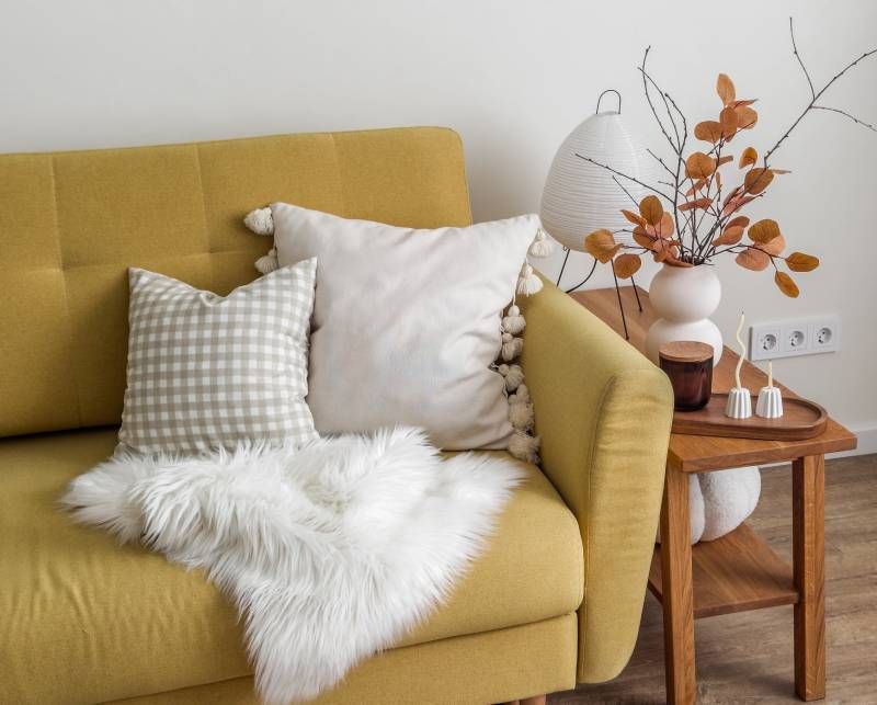 Salón con decoración otoño-invierno con una lámpara de mesa y adornos.ornos.