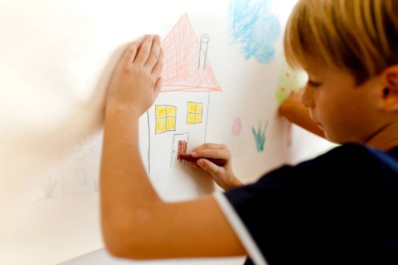 Un niño pintando una casita.