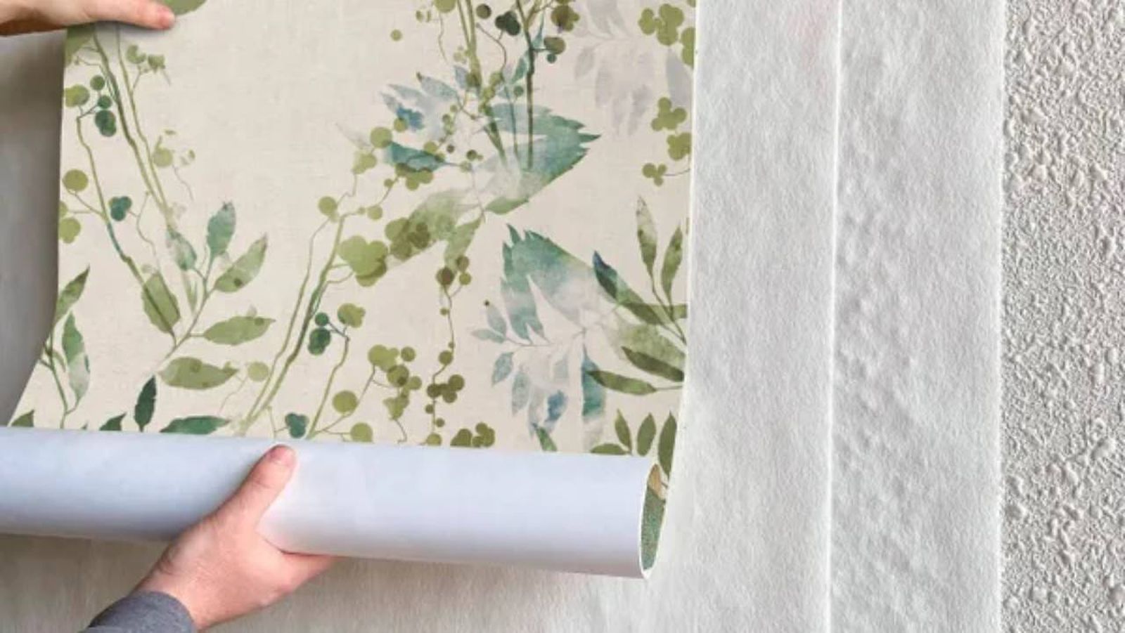 Papel pintado sobre capas de papel cubre gotelé en una pared.