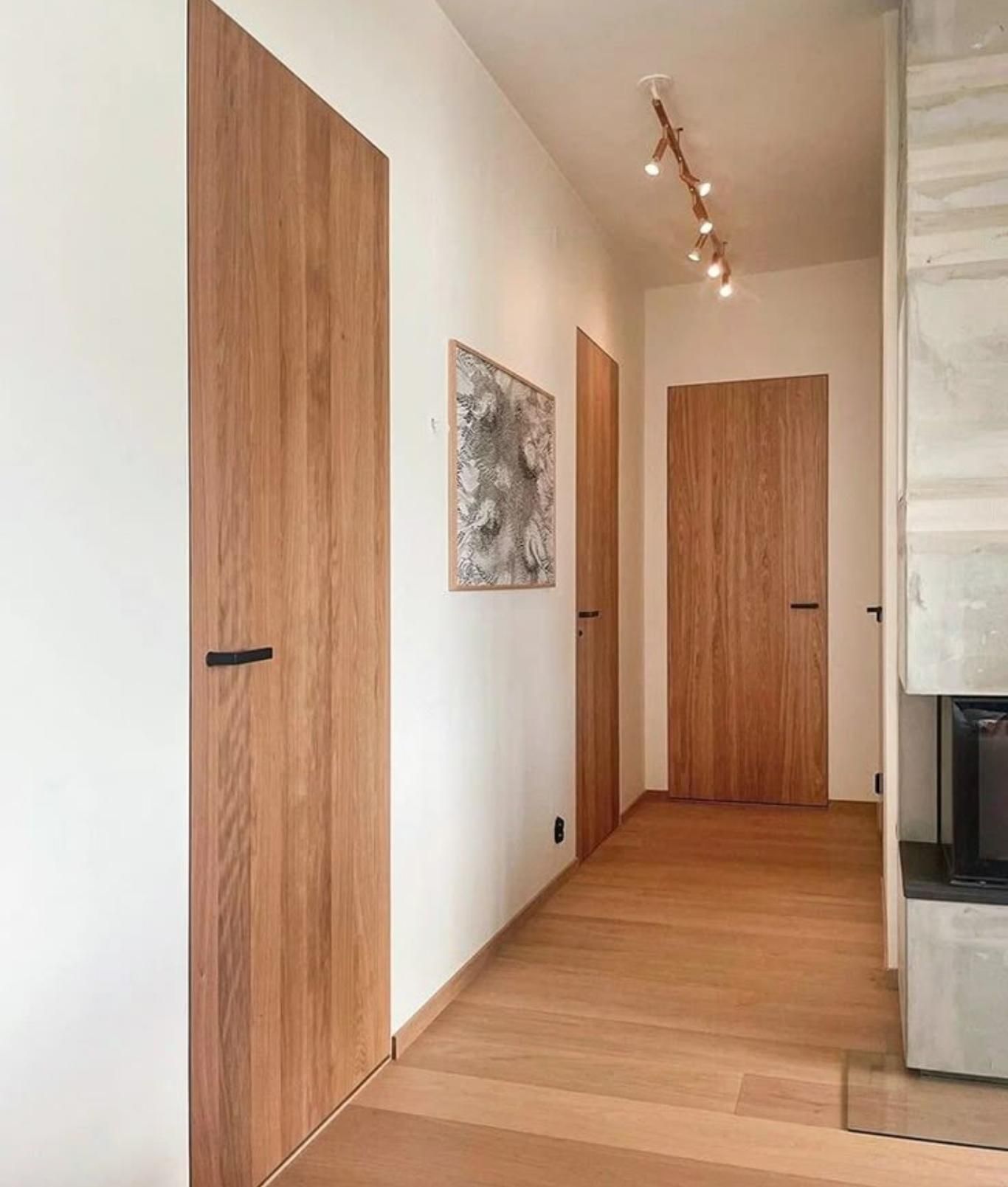 Rincón de casa con puertas y suelo de madera en tonos similares.