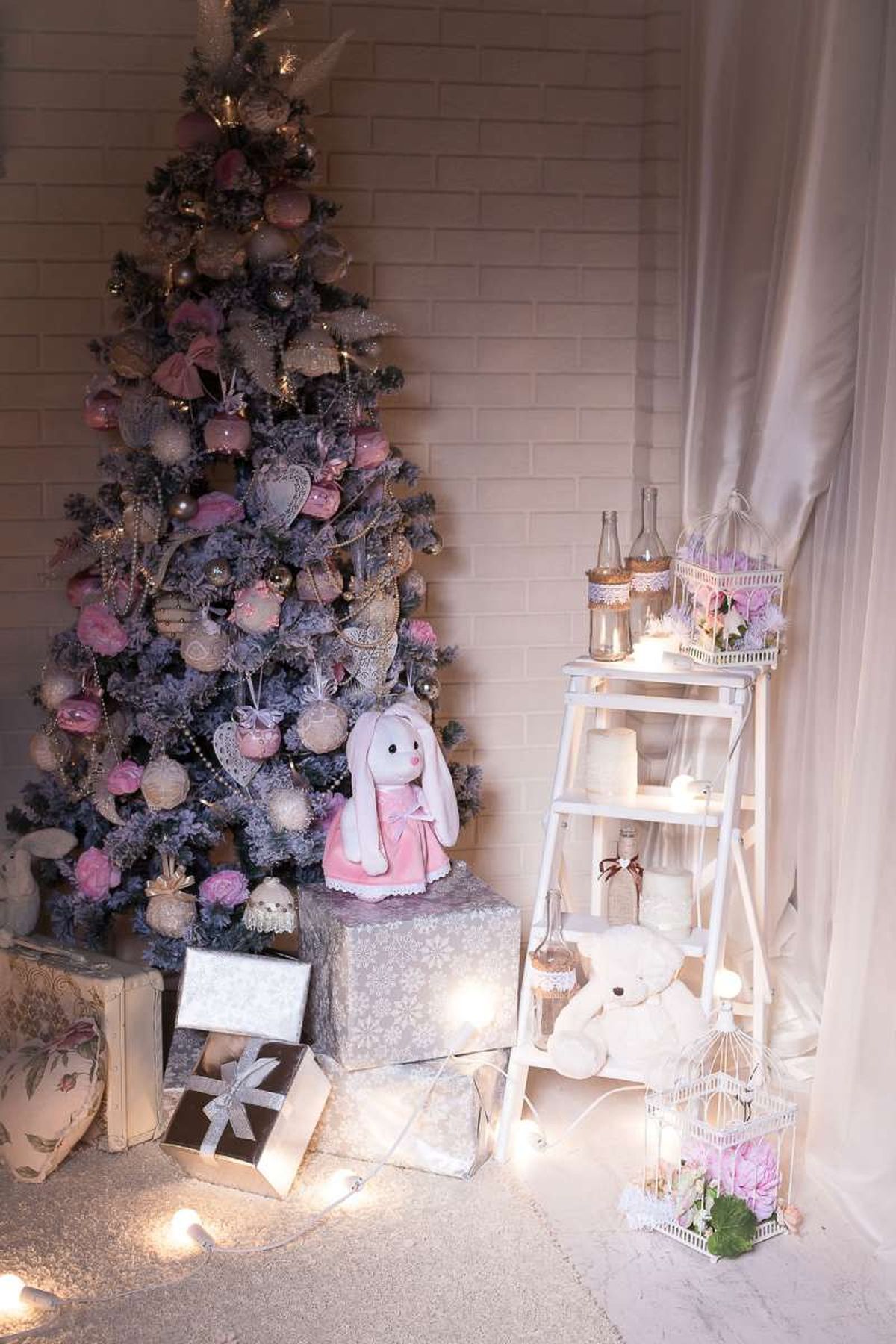 Árbol de Navidad con adornos rosa con el pie decorado con regalos.