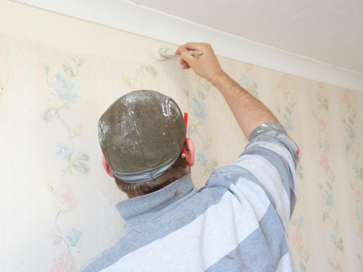 Hombre pintando sobre papel pintado.