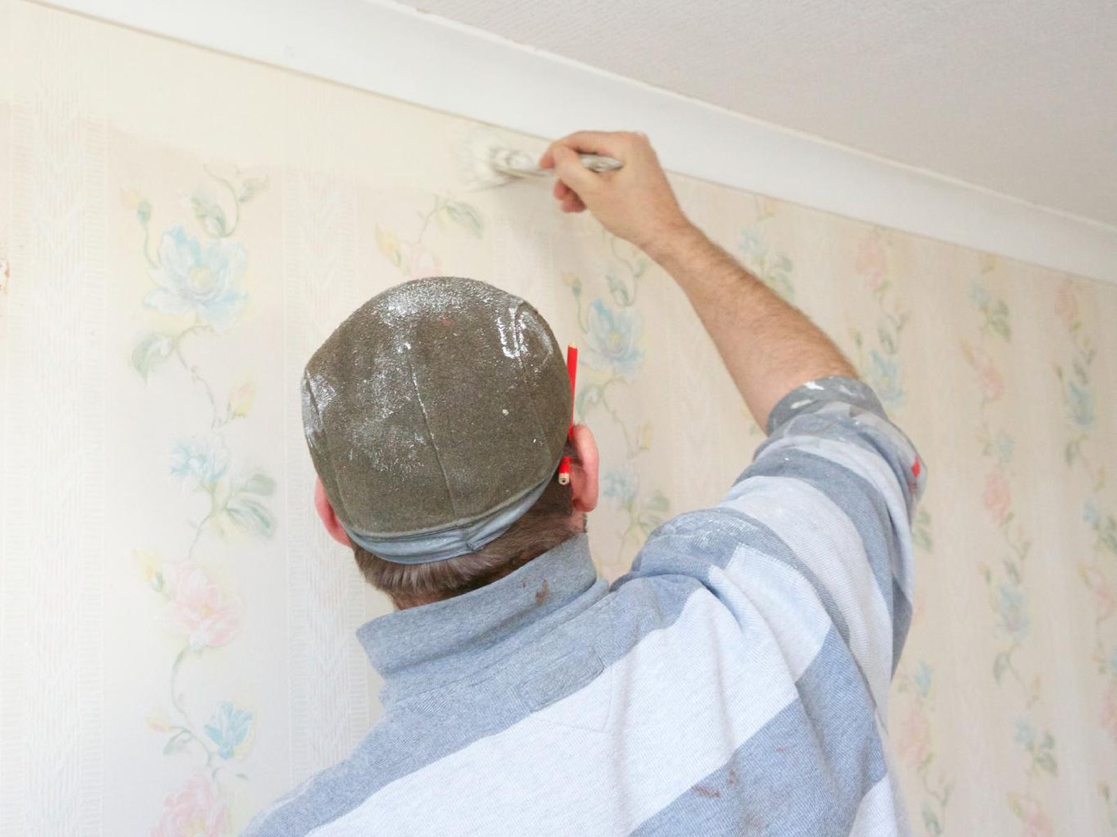 Hombre pintando sobre papel pintado.
