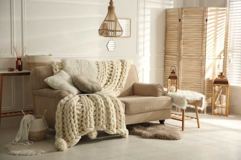 Salón beige con manta de lana gruesa.
