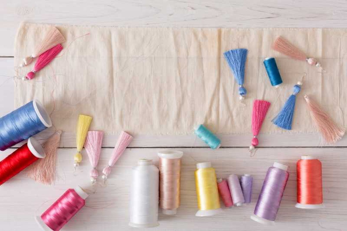 Pendientes de flecos artesanales e hilos para elaborarlos.