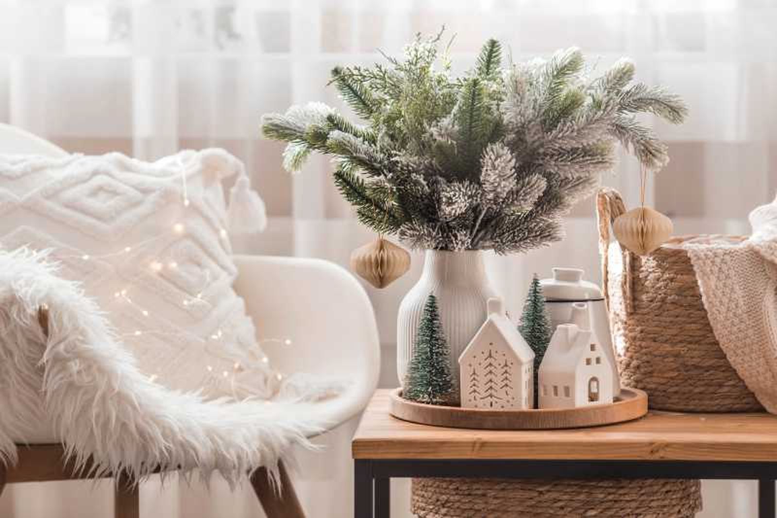 Salón con jarrón con ramas de pino y casitas decorativas.