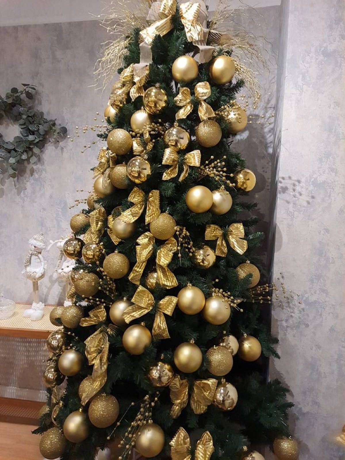 Árbol de Navidad con lazos y adornos dorados.