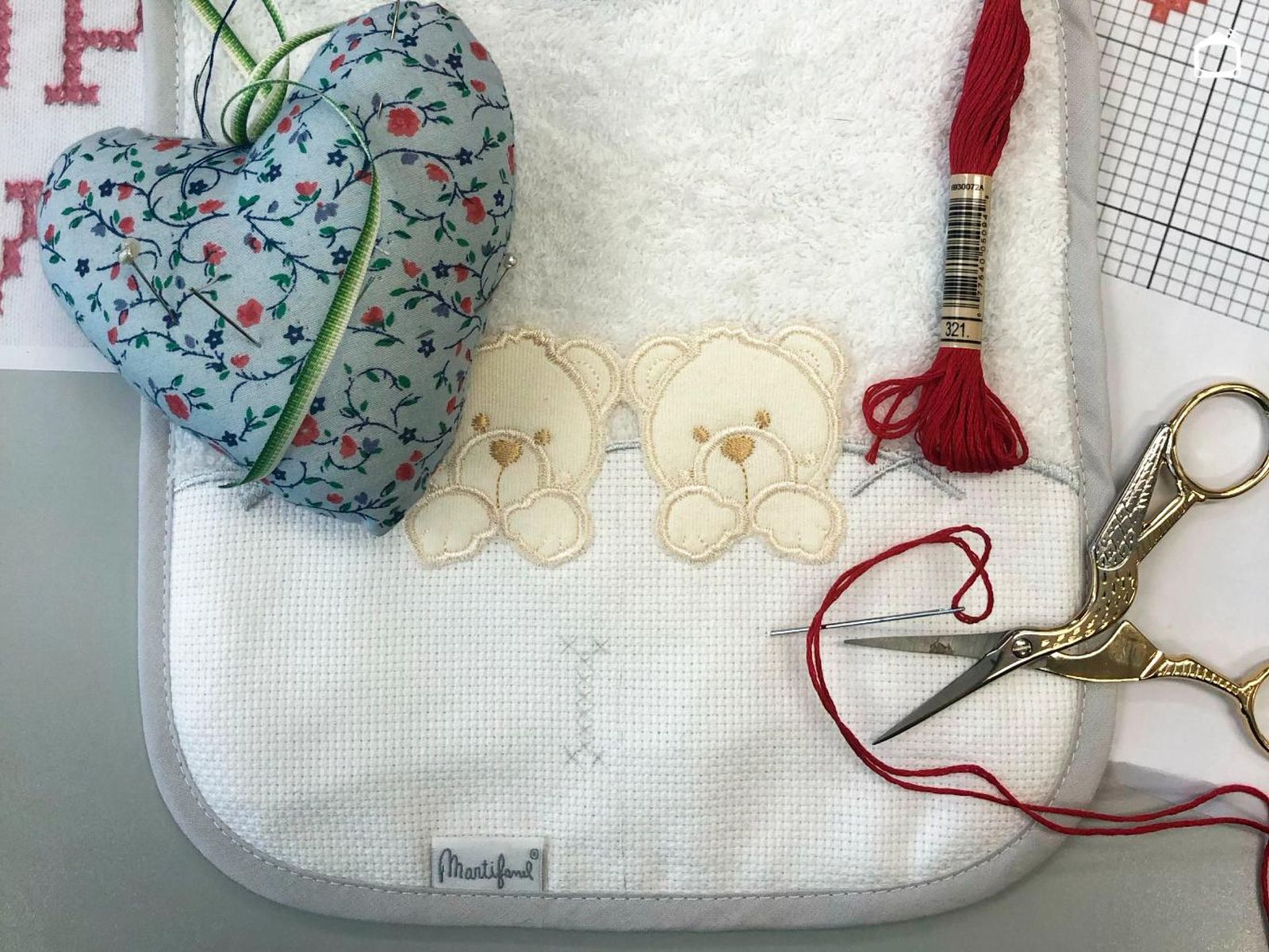Materiales para bordar un babero con punto de cruz.