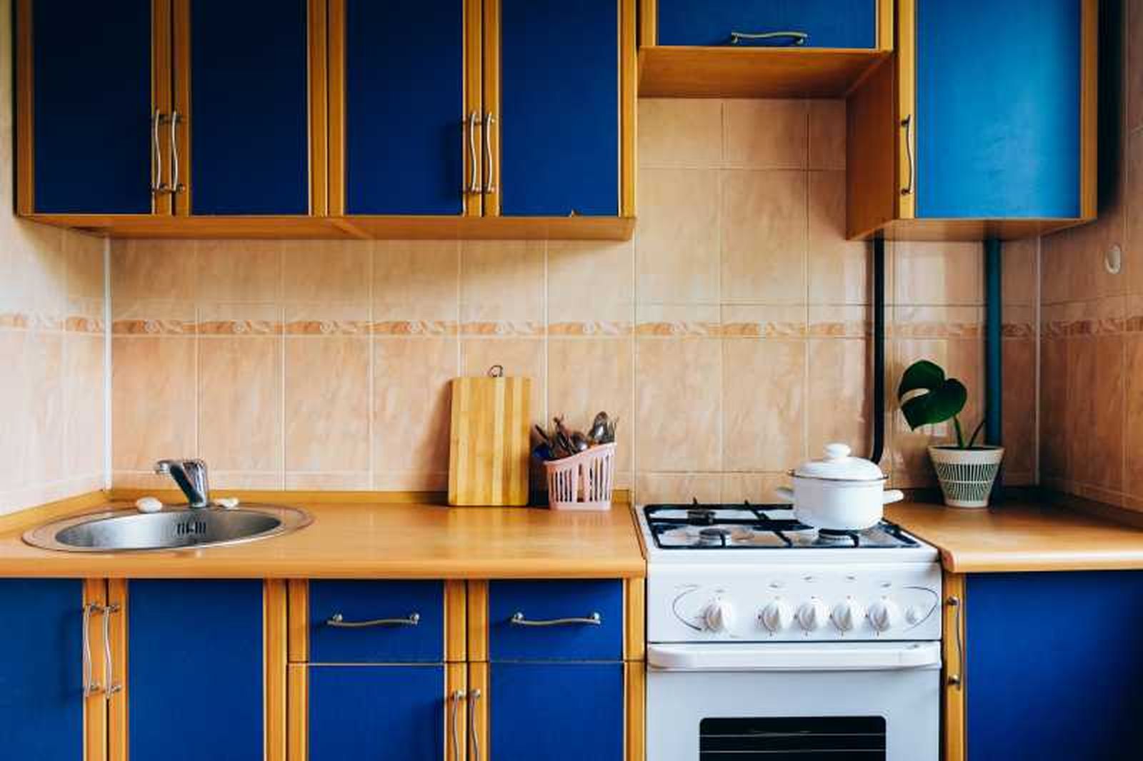 Cocina anticuada en azul y marrón con electrodomésticos blancos.r.
