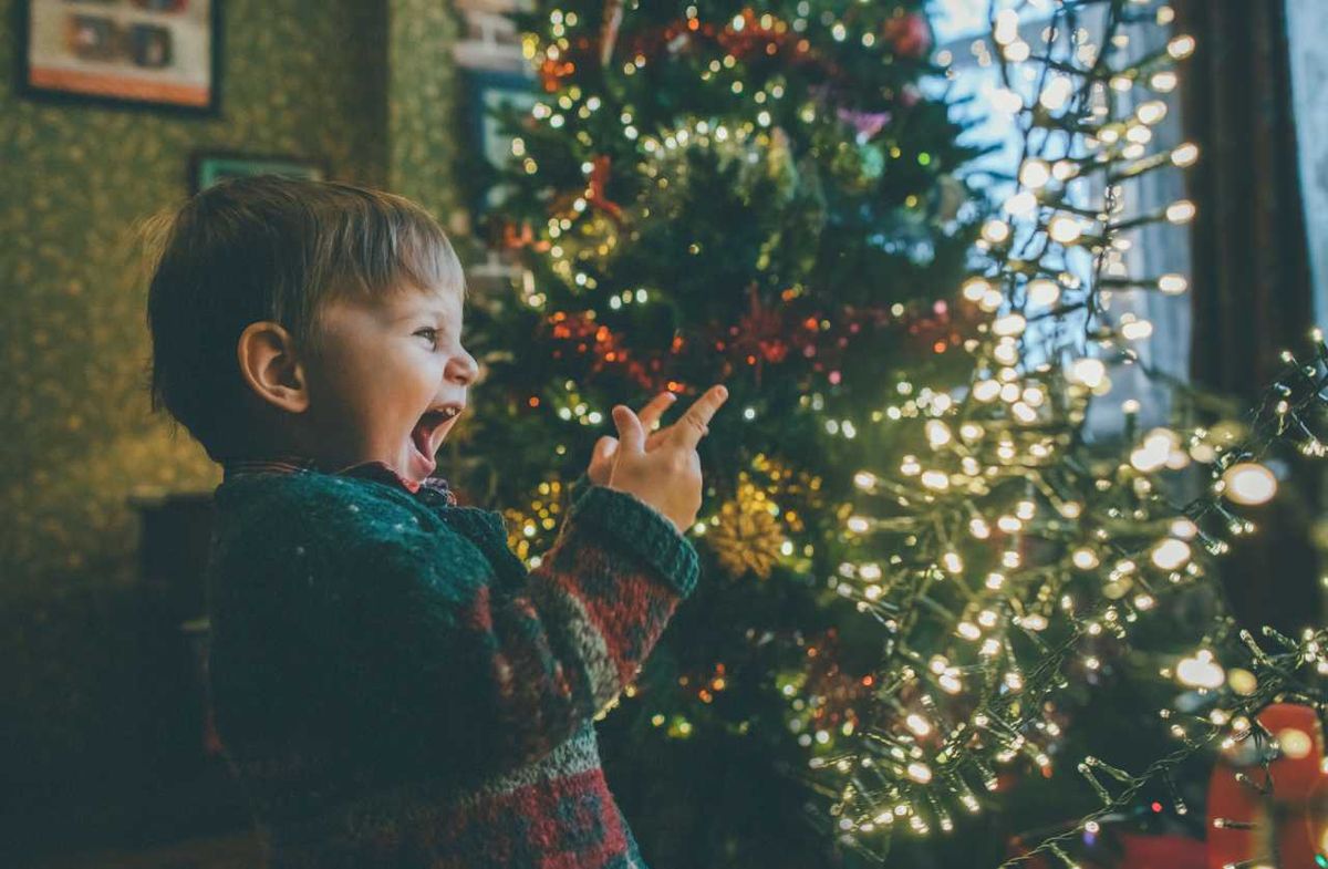 Niño sonriendo frente al árbol de Navidad.