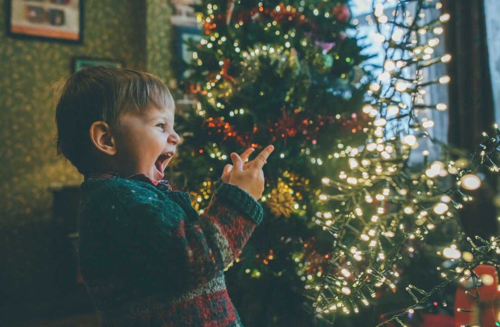 Niño sonriendo frente al árbol de Navidad.