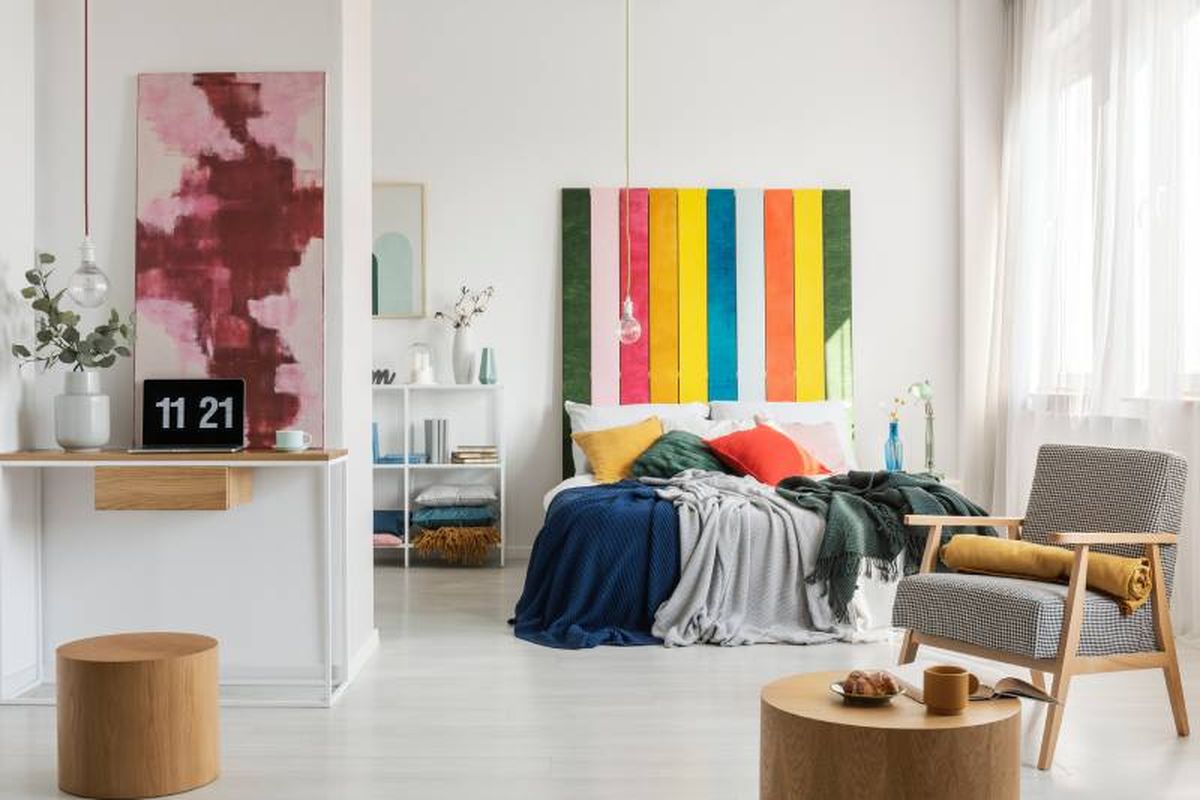 Dormitorio juvenil con cabecero de cama pintado de colores.