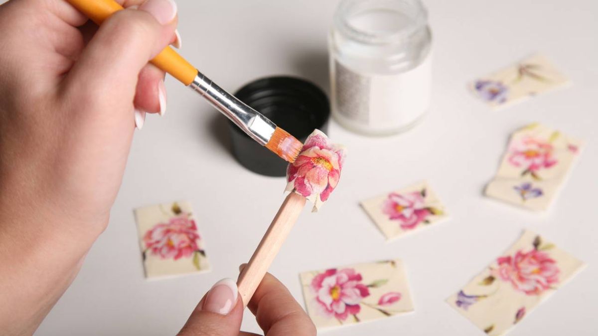 Manos de mujer aplicando barniz-cola para decoupage.