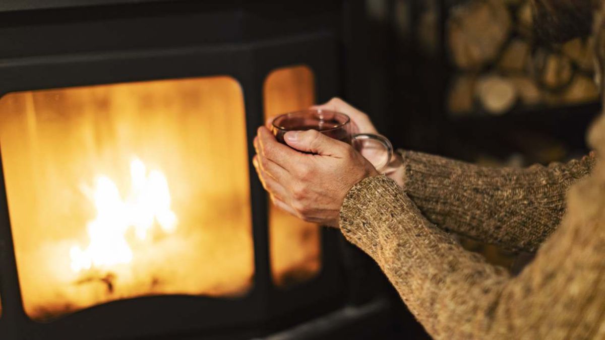 Persona se calienta las manos frente a una chimenea