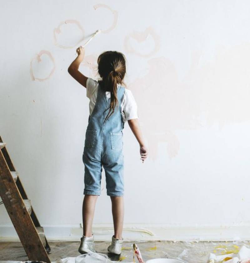 Niña pintando la pared de su dormitorio.
