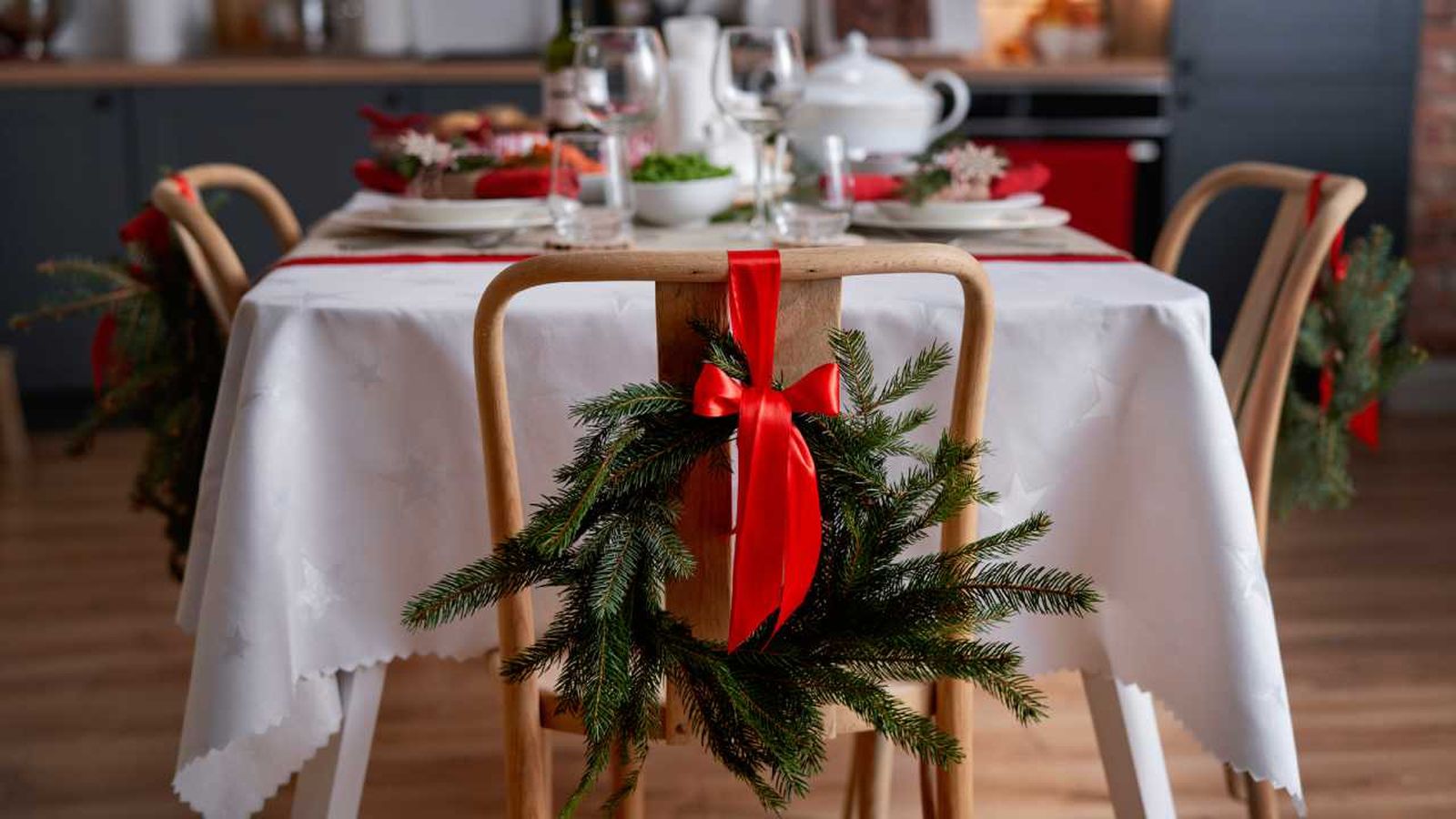 Sillas de la mesa del comedor decoradas con un lazo rojo de Navidad.