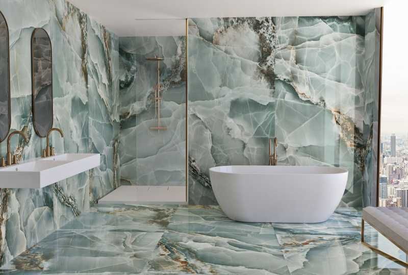 Baño elegante con paredes y suelos de mármol verde.