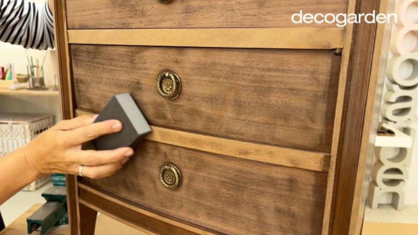 Mano lijando un mueble antiguo de madera con una esponja de tiza.