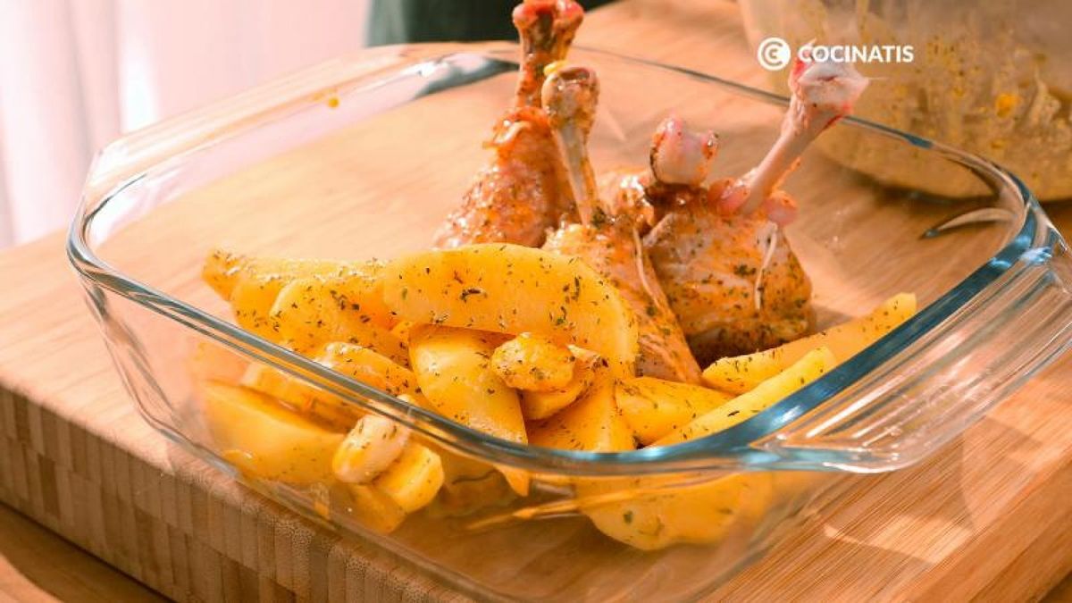 Pon las patatas y el pollo sazonados en una fuente de horno