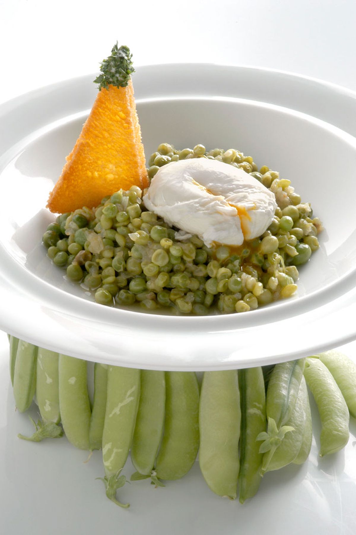 Guisantes con huevos escalfados y pan frito