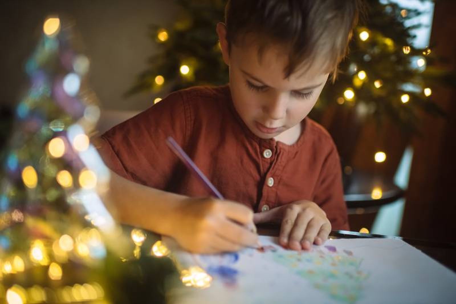 Niño pintando un árbol de Navidad.