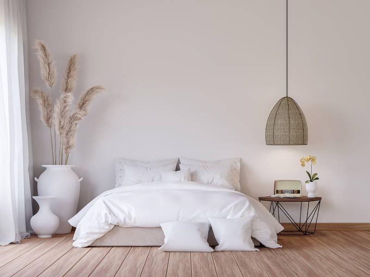 Dormitorio de estilo minimalista en blanco y madera decorado con planta y jarrones.