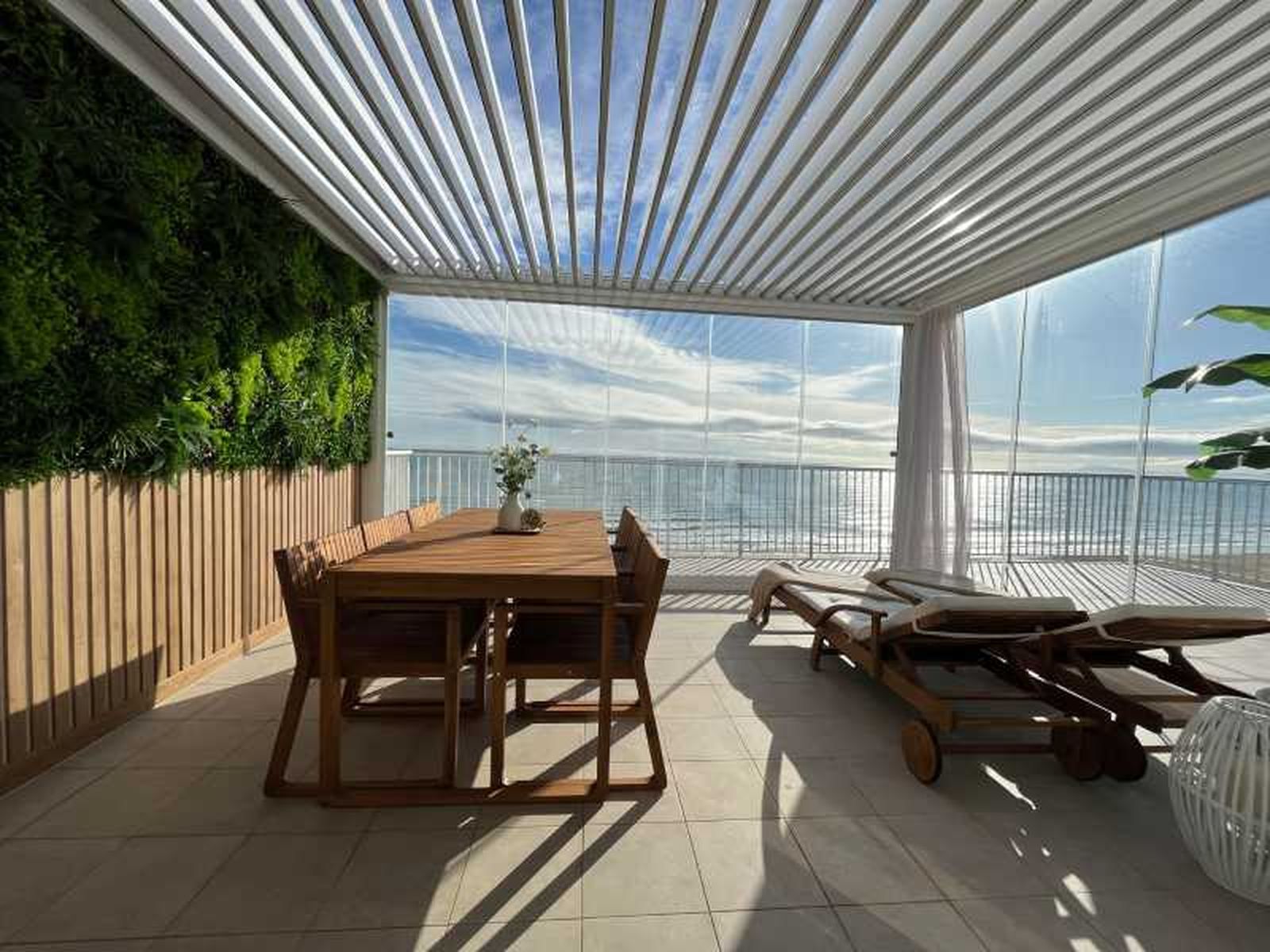 Terraza con pérgola bioclimática con jardín vertical.