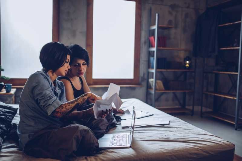 Dos mujeres mirando papeles en la cama.