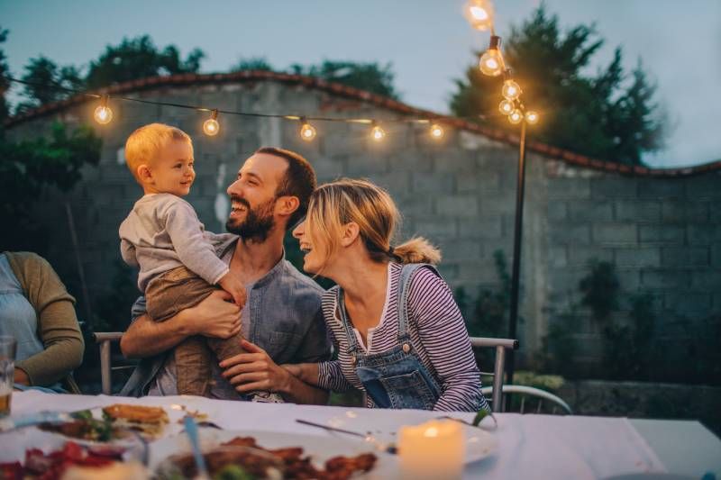 Pareja con un bebé en una cena familiar en el exterior.