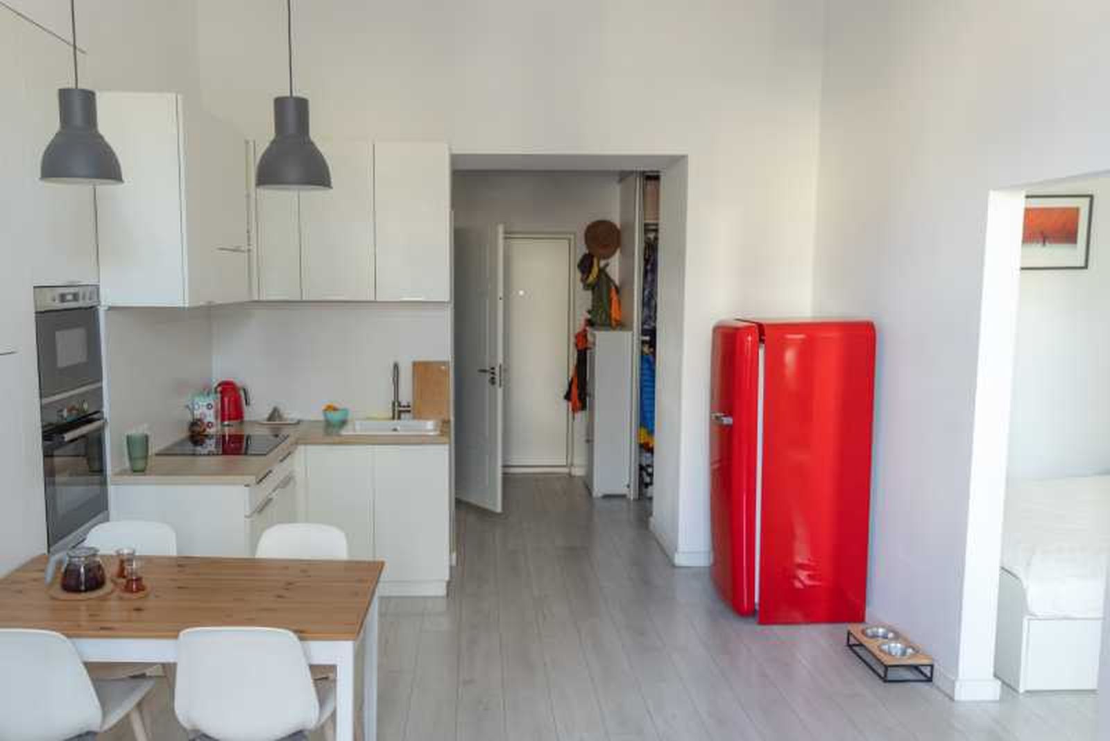 Estudio pequeño decorado en blanco con nevera roja.