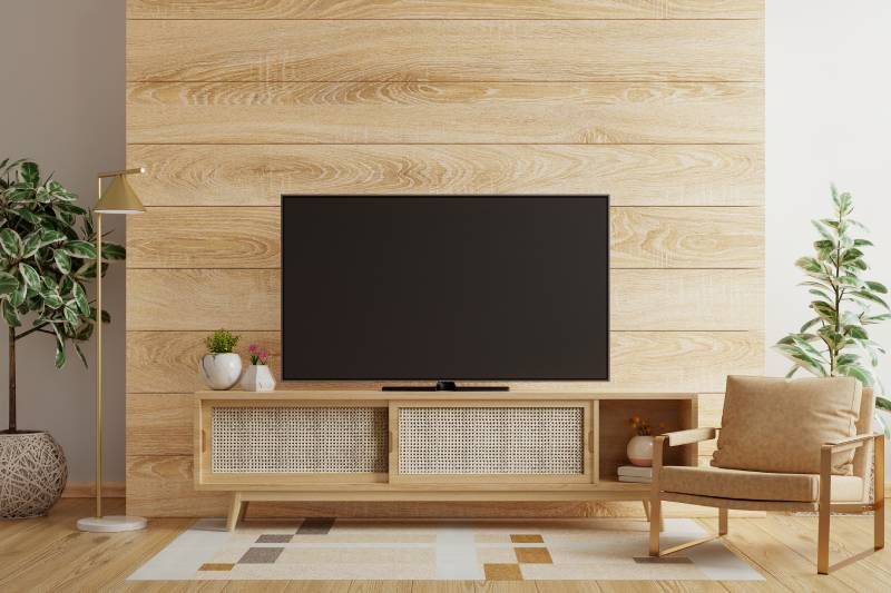 Salón con pared de televisión decorada con madera y plantas verdes.