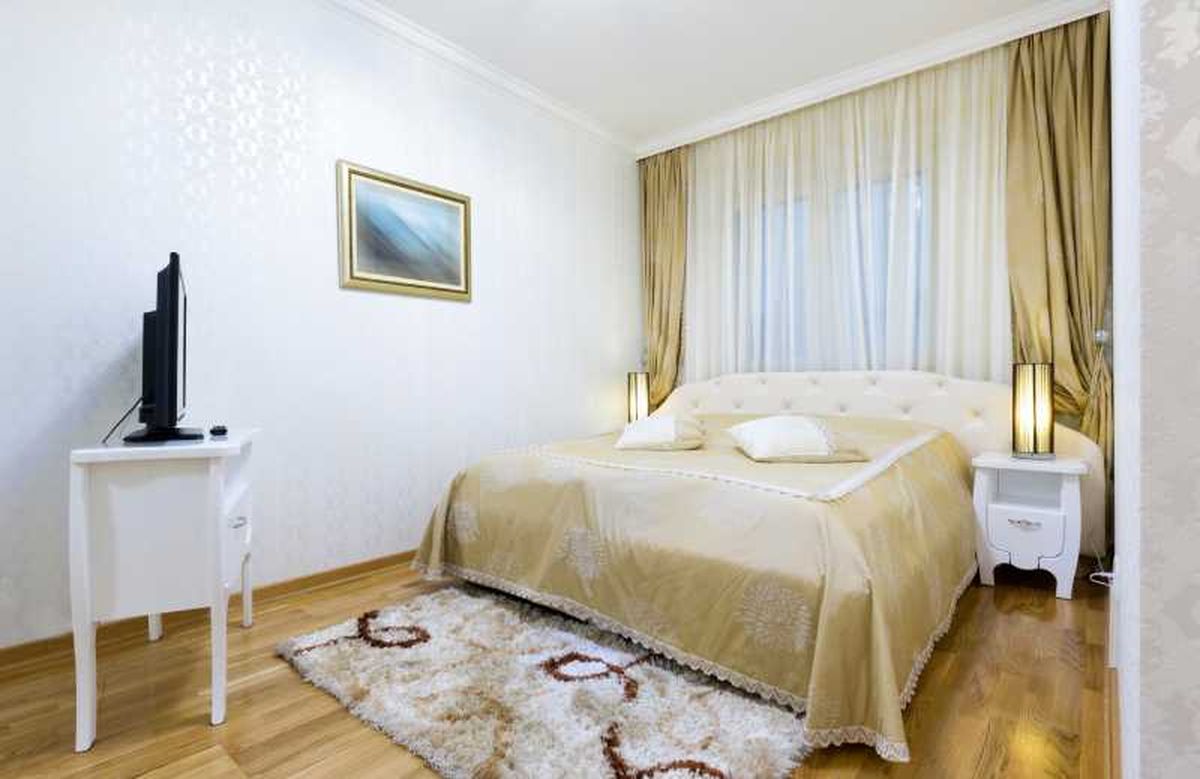 Dormitorio pequeño con cortinas finas en dorado.