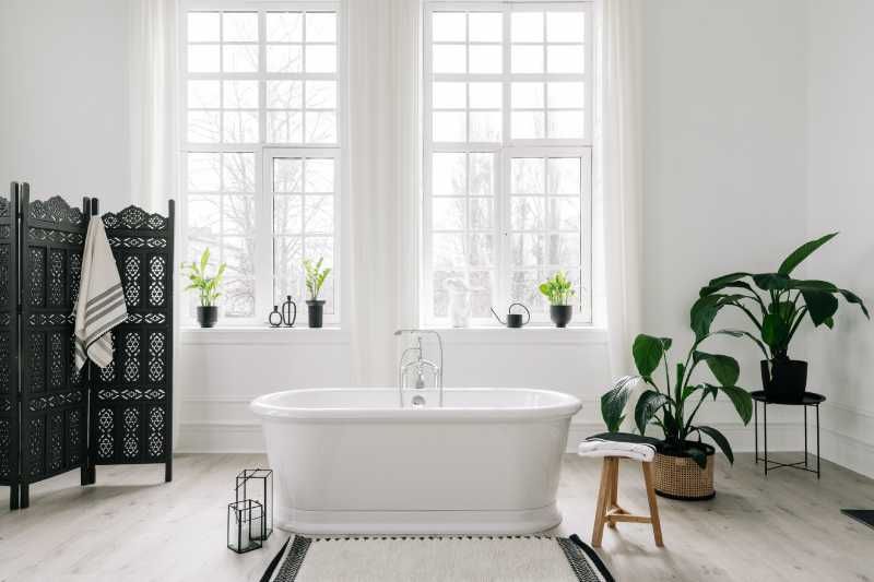 Baño elegante con bañera y plantas.