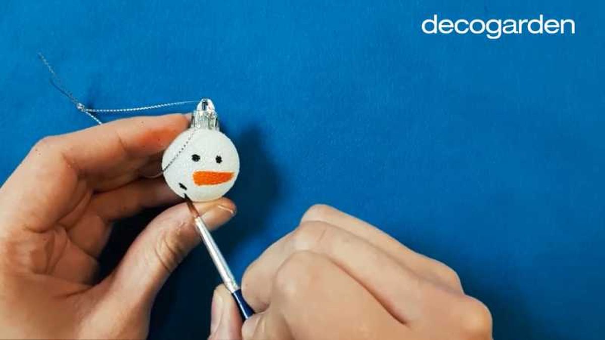 Pintar un muñeco de nieve en una bola de Navidad.