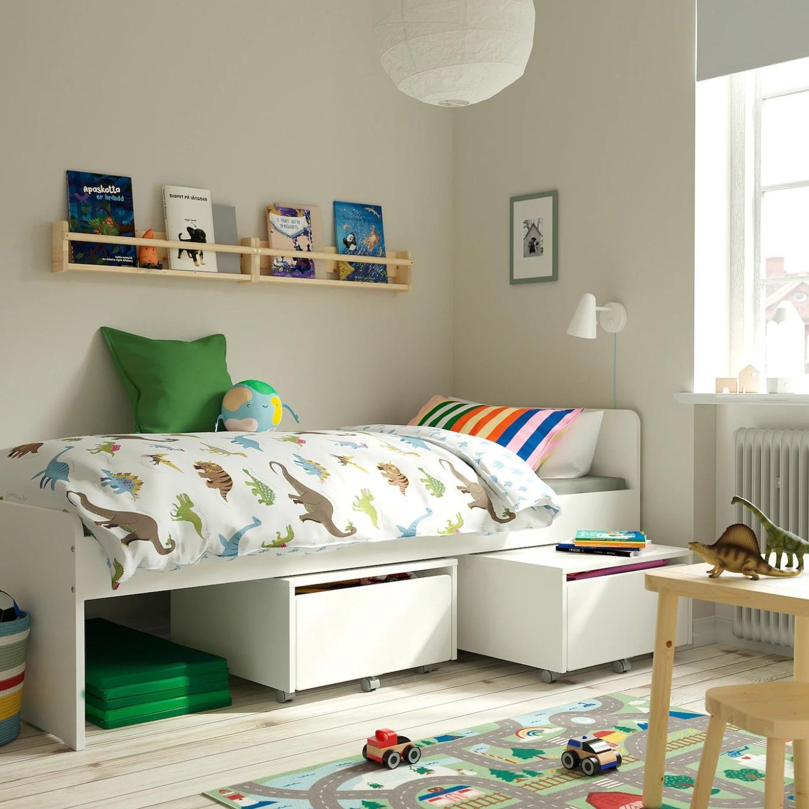 Cama con colcha de dinosaurios.