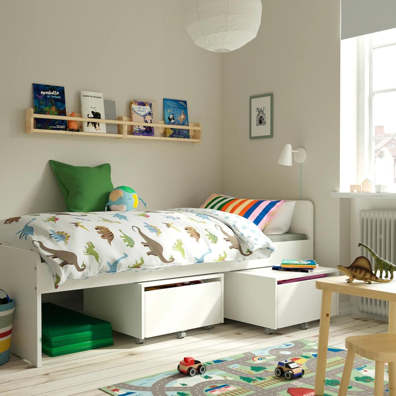 Cama con colcha de dinosaurios.