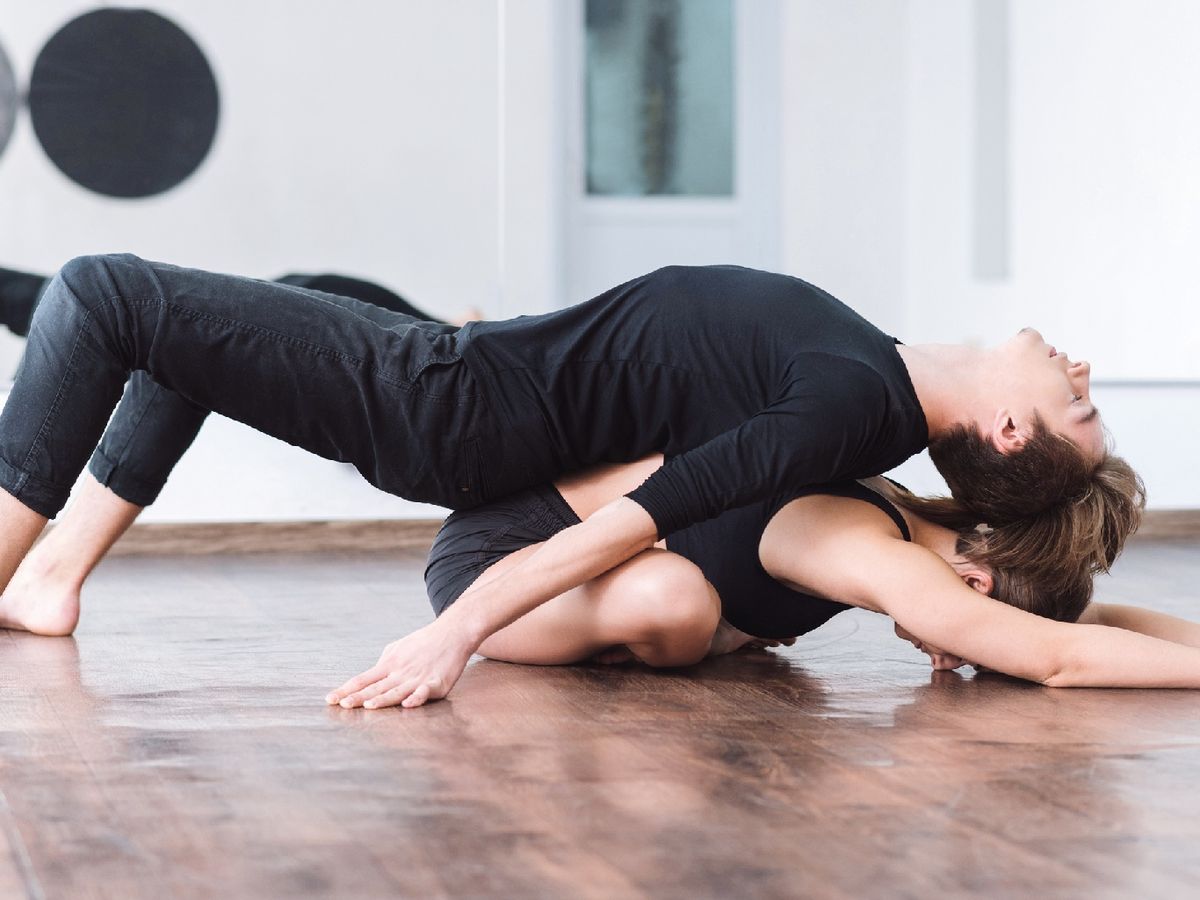 Postura de yoga del doblado hacia adelante en pareja