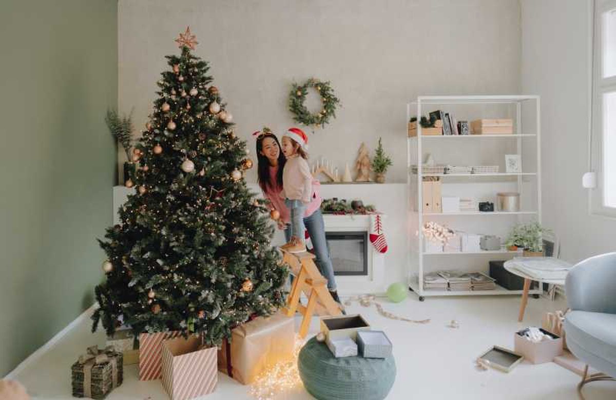 Familia decorando el salón con árbol de Navidad grande.