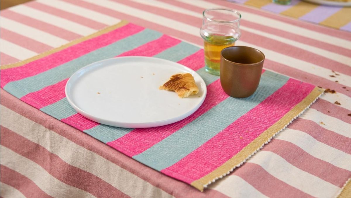 Mesa con mantel individual de rayas rosas y verdes.