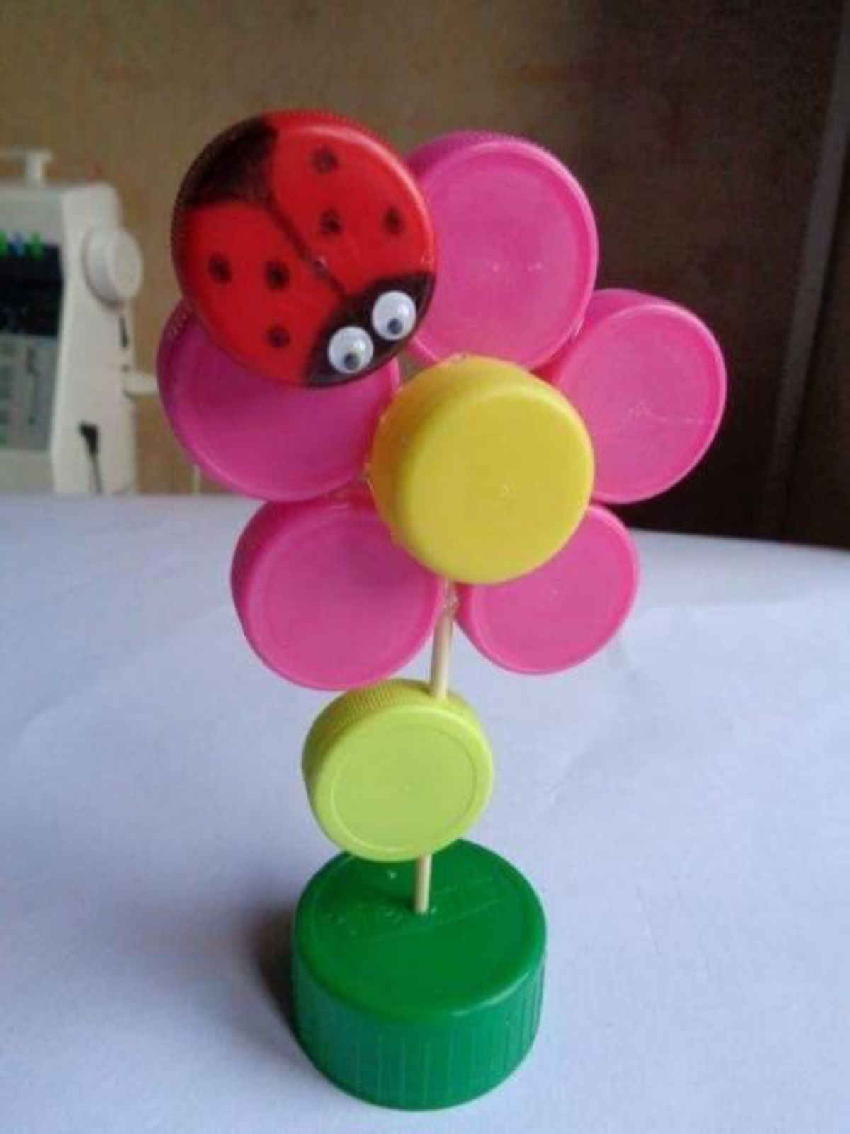 Adorno de flor con mariquita hecho con tapones de plástico.
