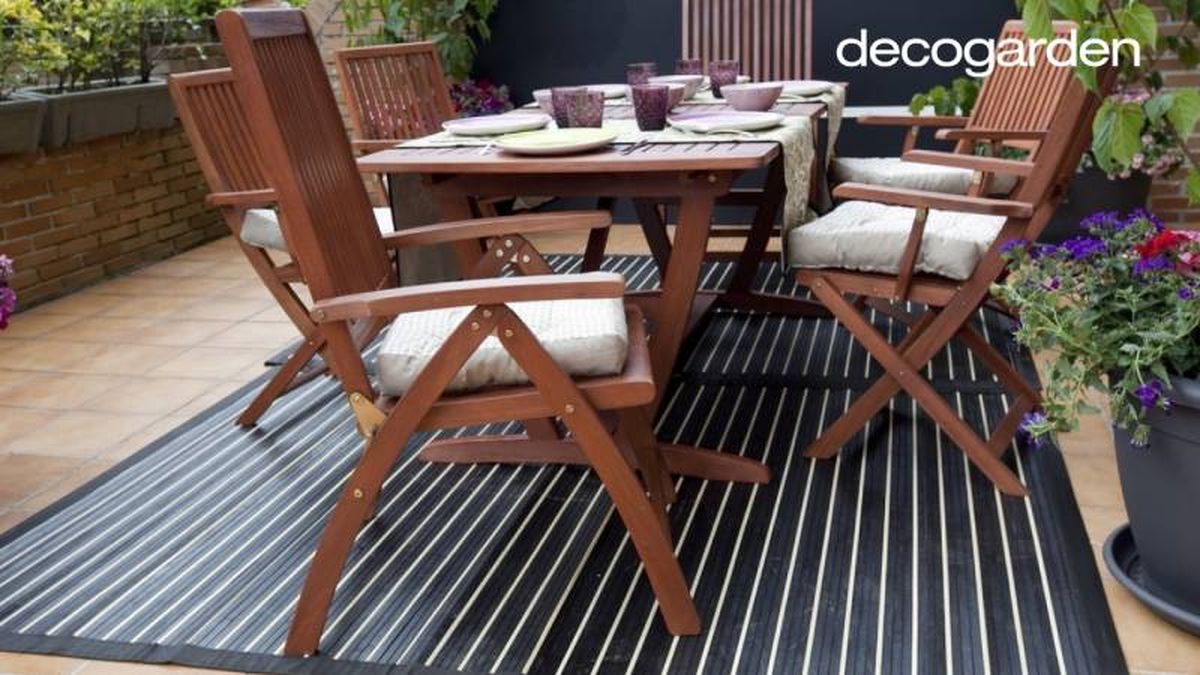 Terraza decorada con mesa y sillas de madera y alfombra vinílica.