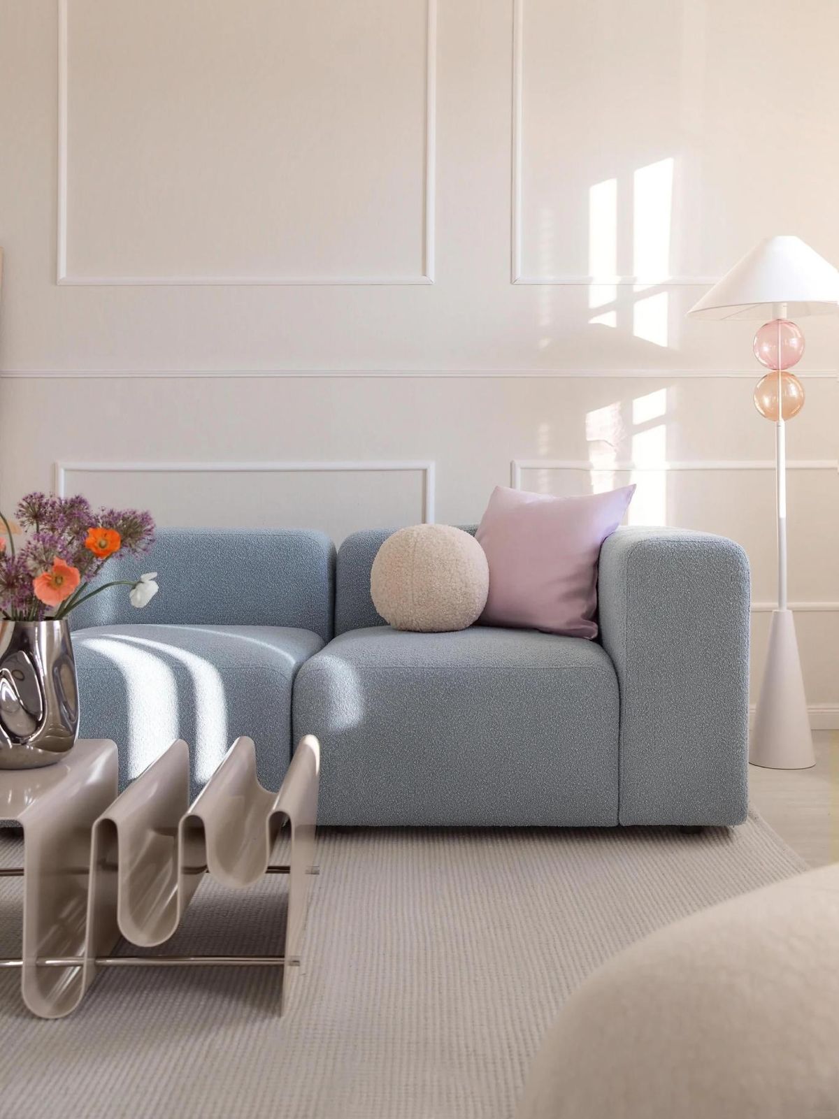 Salón primaveral con sofá azul y mesa moderna con forma ondulada.