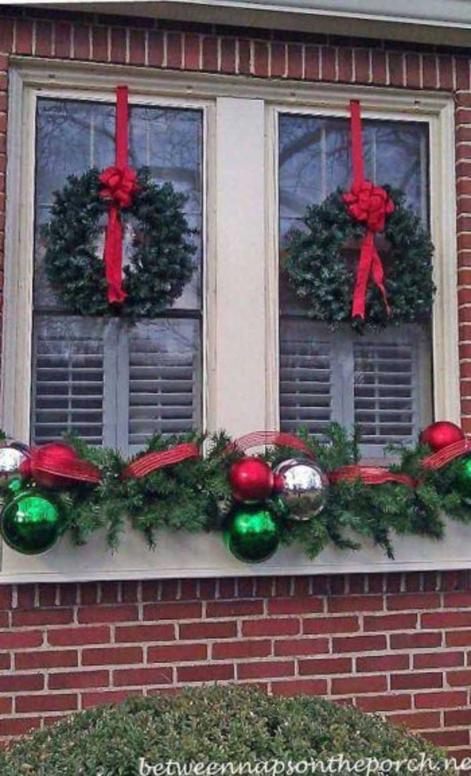 Ventana decorada con dos coronas navideñas en los laterales.
