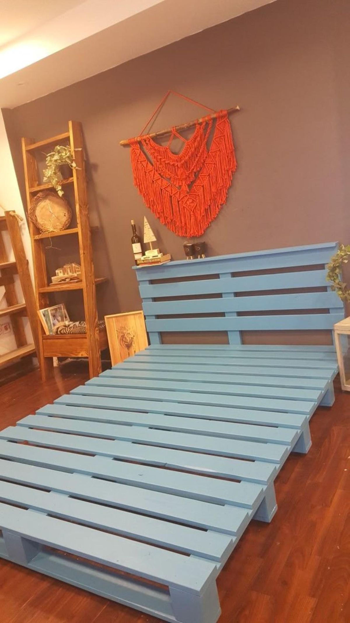 Cabecero y somier de cama hecho con palets y pintado de color azul.