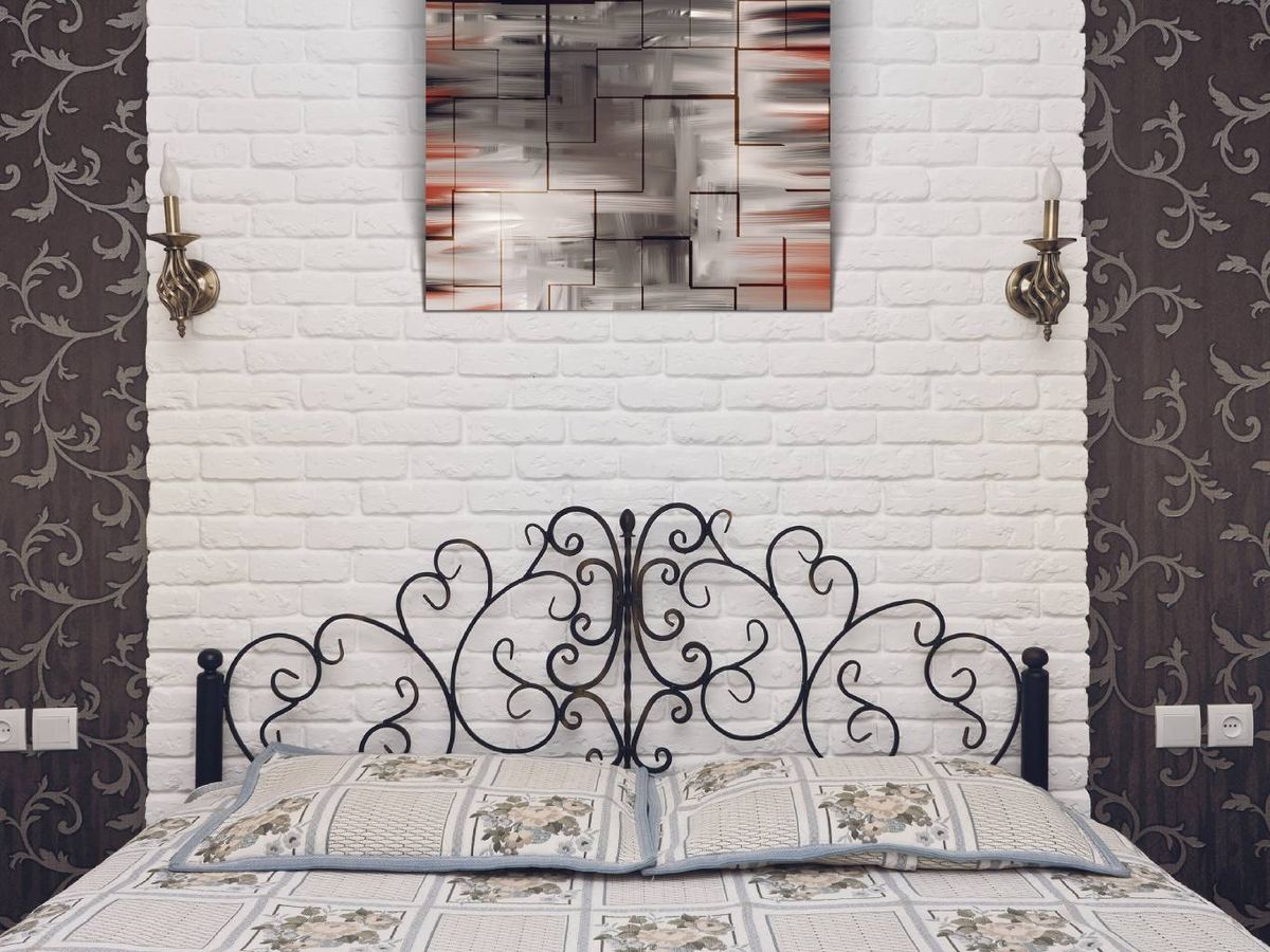 Cabecero de forja negra decorado con volutas, perfecto para un dormitorio con aire vintage.