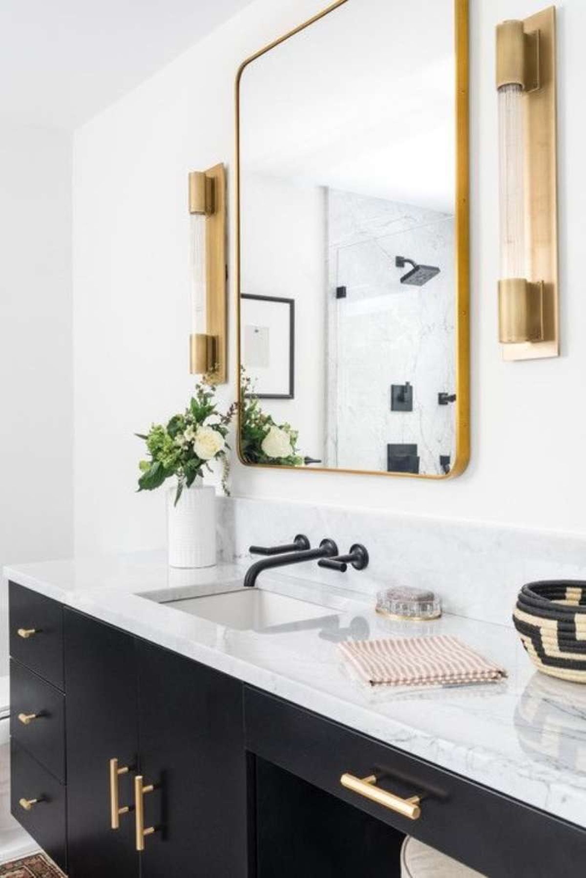 Baño nórdico con grifería negra y complementos dorados.