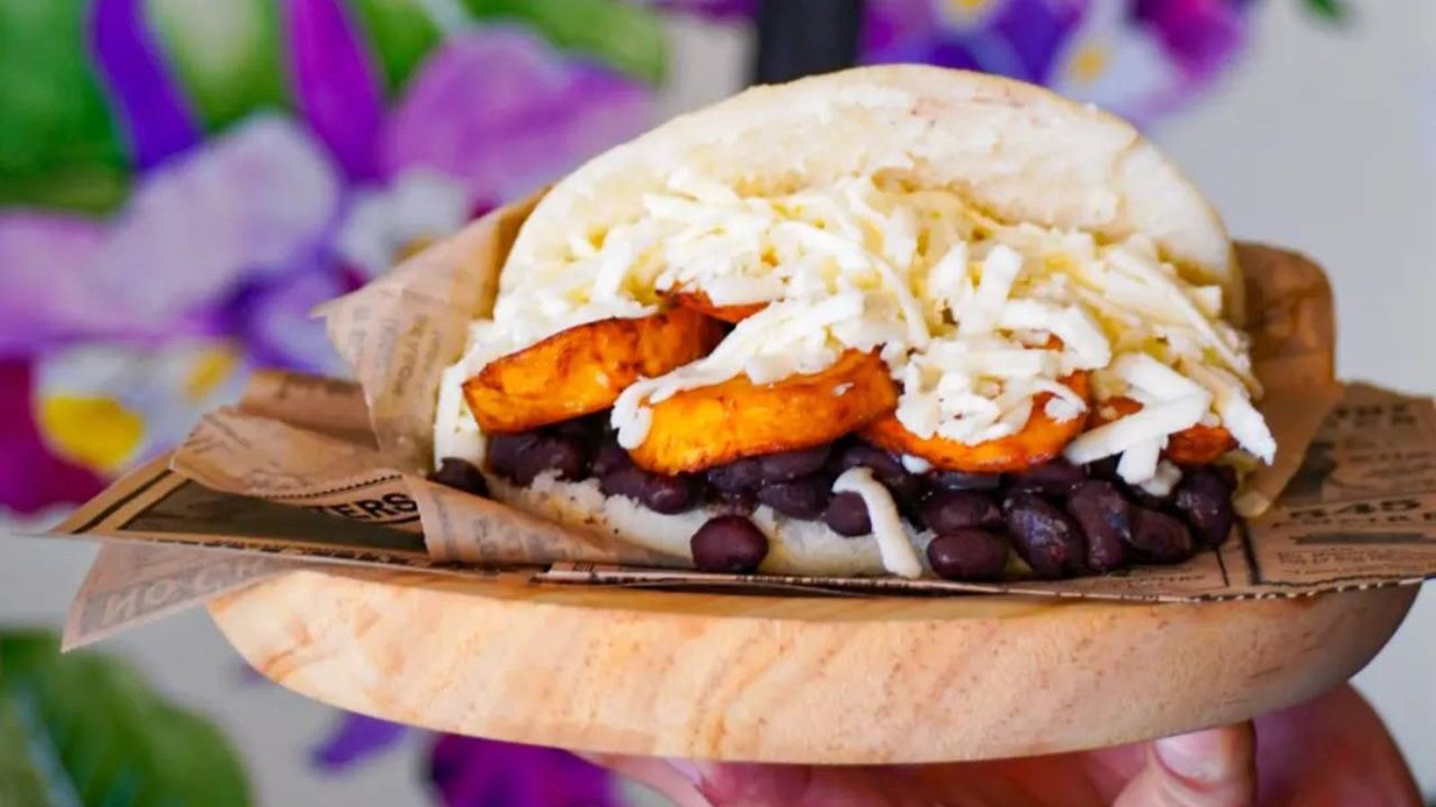 Arepa vegetariana de frijoles negros, tajada fritas y queso rallado