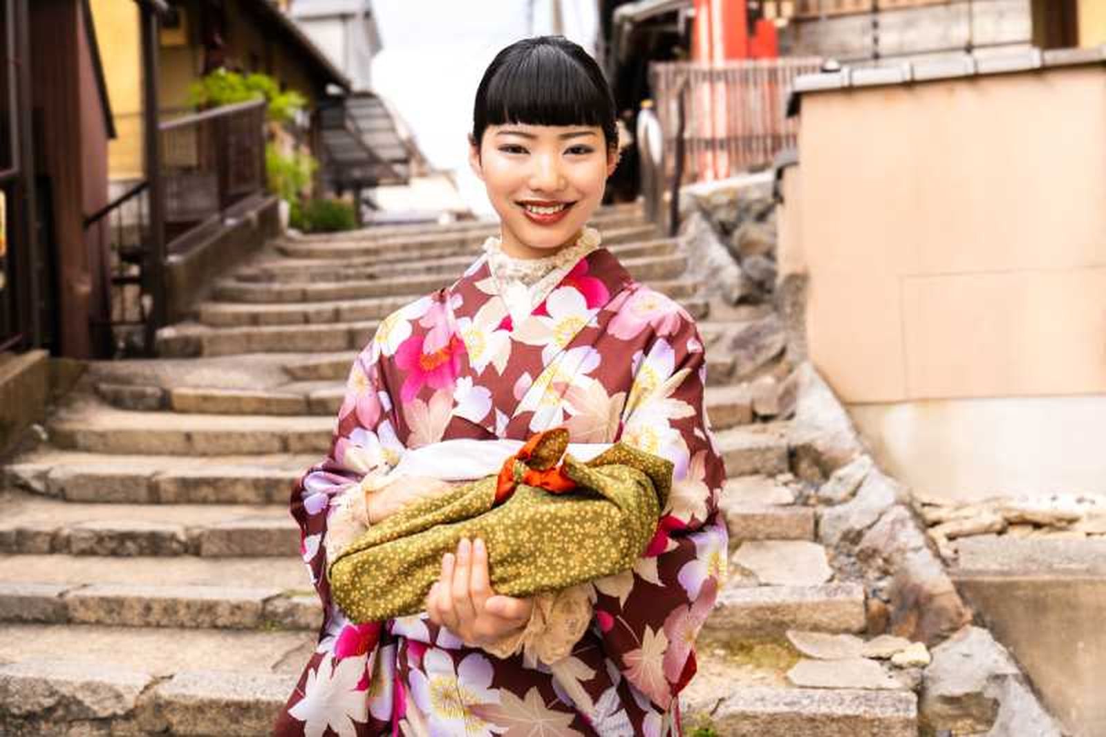 Mujer tradicional japonesa con un paquete envuelto en tela furoshiki.