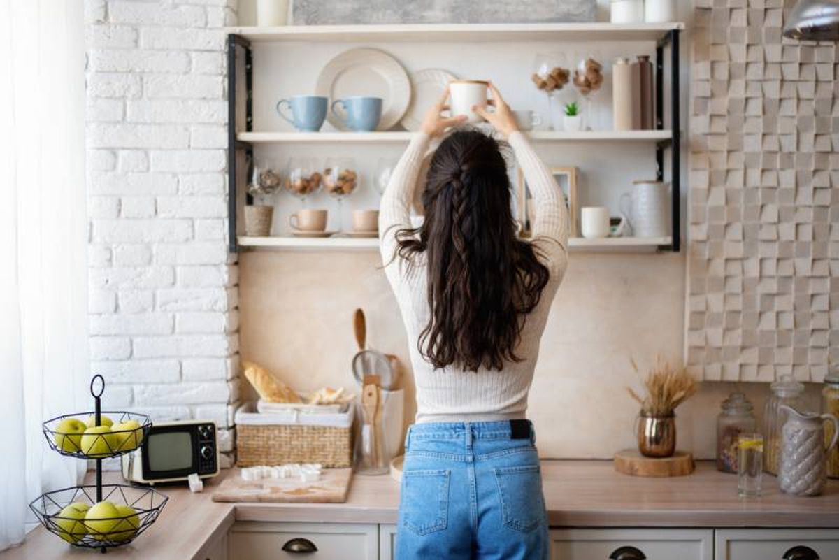 Mujer organizando la estantería de la cocina.